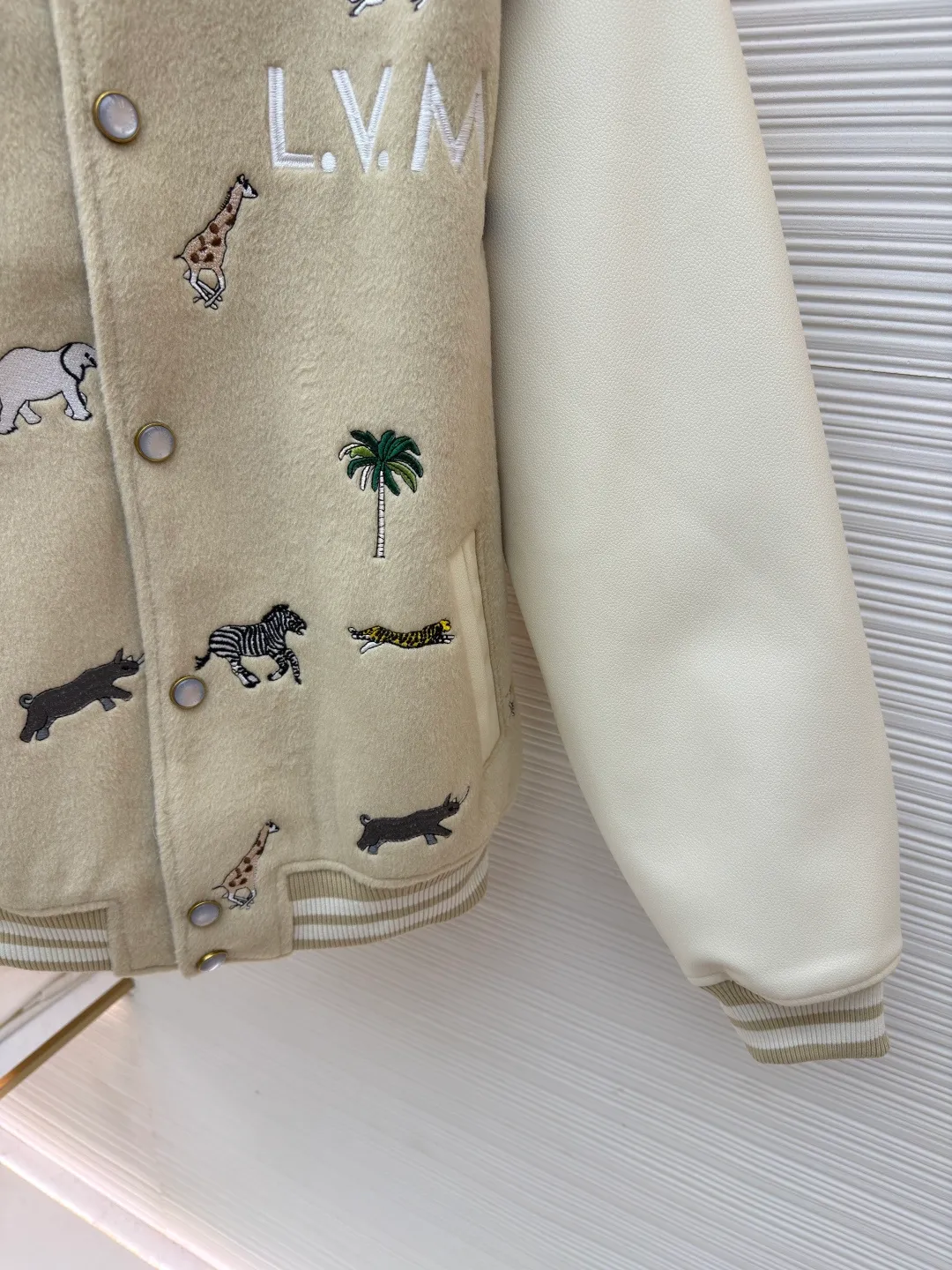 LOUIS VUITTON animal embroidered baseball uniform ●Original version: 48000 purchased and developed ●Item number: 1682284-B90 ●Fabric: cotton fabric ●Technology: embroidery production ●Color: apricot ●Version: fitted version ●Weight: about 1070 grams ●Size: 46-48-50-52 ●Description: The main body of this Louis Vuitton embroidered baseball jacket is made of high-quality wool blended fabric, which is crisp and soft. The sleeves are made of eco-friendly artificial leather with a matte texture, which contrasts with the body in terms of material and touch. The animal, palm tree and other patterns on the body of the clothing are all completed by hand-stitched embroidery technology, using multi-color embroidery threads to embroider in layers. The patterns are three-dimensional and vivid, and the stitching in the details is fine and even. The letter logo uses flat embroidery technology, and the font outline is clear and regular. The ribbed collar, cuffs and hem of the jacket are made of high-elastic knitted fabric, which will not loosen easily after being worn for a long time. The metal snaps on the placket are custom-made hardware with a thick texture and anti-oxidation. The overall tailoring is a loose oversize version, and the splicing uses hemming stitching technology, and the lines are smooth and smooth. Every craft detail is in line with the brand's luxury product production standards, creating a ready-to-wear garment that has both a sense of design and practical wearability. The overall wiring is straight and delicate, the fabric is comfortable and soft, and the color is consistent without color difference. It can be matched with the same style to create a fashionable look and control various occasions. Customized accessories, complete with three standards, same style for men and women!